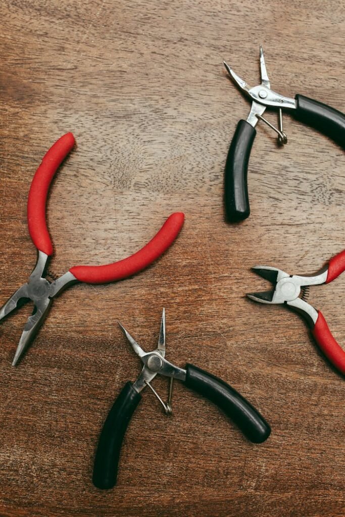 Various pliers arranged on a wooden surface viewed from above.