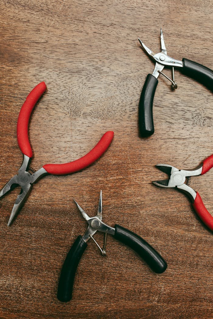Various pliers arranged on a wooden surface viewed from above.